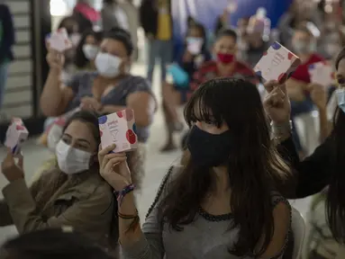 Sejumlah wanita memegang pembalut setelah menerima sumbangan perlengkapan kebersihan wanita di tengah pandemi COVID-19 di favela Paraisopolis, di Sao Paulo, Brasil (24/5/2021). Sumbangan ini disediakan oleh LSM lokal "G10 Favelas". (AP Photo/Andre Penner)