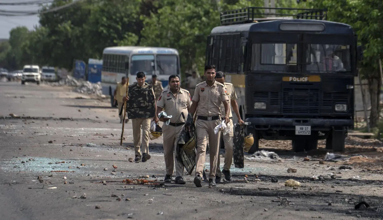 Pecahan kaca dan puing-puing berserakan di jalan saat polisi berpatroli setelah bentrokan komunal di Nuh di negara bagian Haryana, India, Selasa, 1 Agustus 2023. (AP Photo/Altaf Qadri)