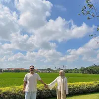 Berlatar sawah yang asri, Kesha Ratuliu tidak melewatkan momen untuk berfoto dengan sang suami. Ia tampil casual chic dengan lengan panjang berwarna putih yang dipadukan dengan kulot dan kerudung berwarna nude. (instagram/kesharatuliu05)
