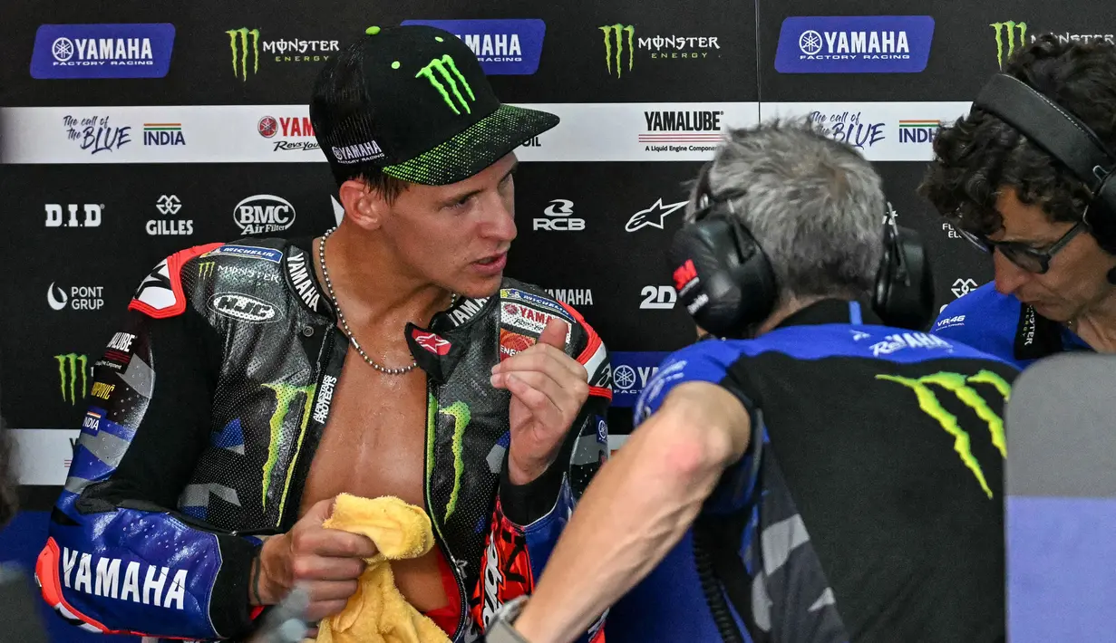 Pembalap Monster Energy Yamaha MotoGP, Fabio Quartararo (kiri) berbicara dengan anggota tim di garasi saat latihan bebas pertama MotoGP Grand Prix Malaysia di Sirkuit Internasional Sepang, 1 November 2024. (MOHD RASFAN/AFP)