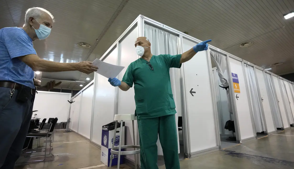 Pekerja medis memberikan arahan saat orang-orang tiba untuk divaksin COVID-19 di pusat vaksinasi darurat Belgrade Fair di Belgrade, Selasa (17/8/2021). Serbia mulai memberikan dosis ketiga atau booster untuk mereka yang sebelumnya telah divaksinasi minimal 6 bulan lalu. (AP Photo/Darko Vojinovic)