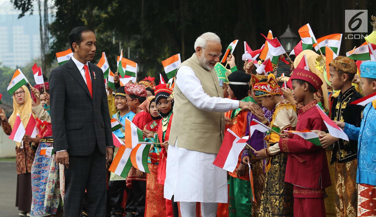 Perdana Menteri (PM) India, Narendra Modi didampingi Presiden Joko Widodo (Jokowi) bersalaman dengan murid Sekolah Dasar berpakaian adat Indonesia dalam upacara penyambutan di Istana Merdeka, Jakarta, Rabu (30/5). (Liputan6.com/Angga Yuniar)