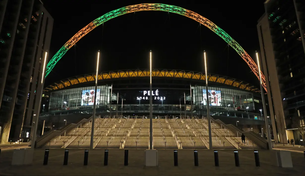 Lengkungan Stadion Wembley menyala dalam warna Brasil dan layar menampilkan gambar Pele setelah pengumuman bahwa mantan pemain sepak bola Brasil itu meninggal dunia, London, Inggris, 29 Desember 2022. Edson Arantes do Nascimento atau yang dikenal sebagai Pele, raja sepak bola Brasil yang menang rekor tiga Piala Dunia dan menjadi salah satu tokoh olahraga paling berwibawa abad lalu, meninggal pada usai 82 tahun di di Sao Paulo. (Kieran Cleeves/PA via AP)