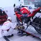 Mekanik bengkel Honda sedang melakukan service sepeda motor.