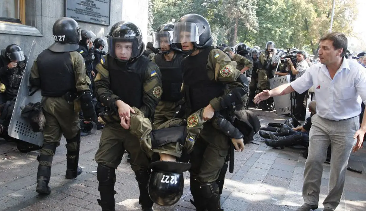Petugas menggotong rekannya yang terluka akibat ledakan di depan gedung Parlemen Ukraina di Kiev, Senin (31/8). Satu petugas tewas dan 90 lainnya terluka dalam aksi yang menentang perubahan UU dasar mengenai desentralisasi. (AFP PHOTO/Yuriy KIRNICHNY)