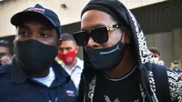 Mantan pemain timnas Brasil, Ronaldinho tiba di bandara El Galeao di Rio de Janeiro, setelah menjalani tahanan rumah di Paraguay, Selasa (25/8/2020). Pria 40 tahun itu sendiri yang mengumumkan hasil tes yang positif Covid-19 di akun Instagram-nya. (AFP/Carl dE Souza)
