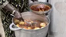Koki Senegal Thiane Ngom menyiapkan "thiebou dieune" tradisional di rumahnya di Dakar pada 15 Desember 2021. Thiebou dieune biasanya dimakan dengan tangan, tapi beberapa orang lebih suka memakannya dengan garpu atau sendok. (SEYLLOU/AFP)