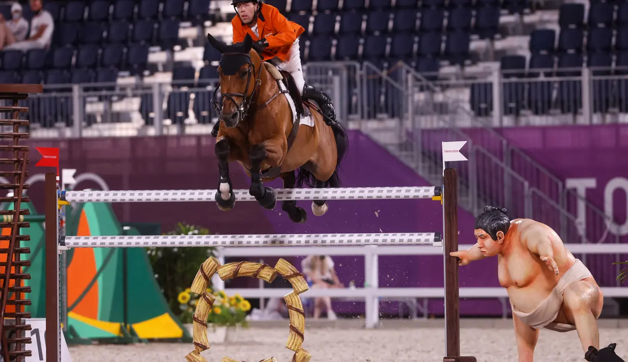 Maikel Van Der Vleuten dari Belanda mengendarai Beauville Z melewati patung pegulat sumo kecil di kualifikasi individu lompat berkuda selama Olimpiade Tokyo 2020 di Equestrian Park di Tokyo (3/8/2021). (AFP/Behrouz Mehri)
