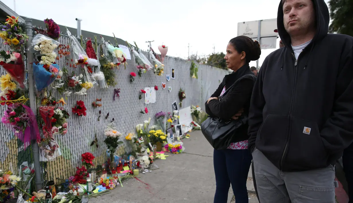 Sejumlah orang berkumpul di tempat peringatan Gudang Terbakar di California, AS, Senin (5/12). Setidaknya ada 30 korban yang tewas dalam peristiwa kebakaran tersebut. (REUTERS / Lucy Nicholson)
