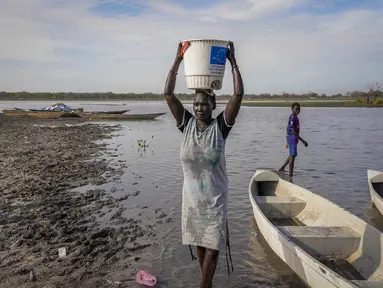 Seorang perempuan membawa air di kepalanya dari rawa, dengan sebagian besar daerah tidak memiliki akses ke air minum bersih karena banjir bertahun-tahun yang belum pernah terjadi sebelumnya, di Canal-Pigi County, Sudan Selatan pada 4 Mei 2023. (AP Photo/Sam Mednick)