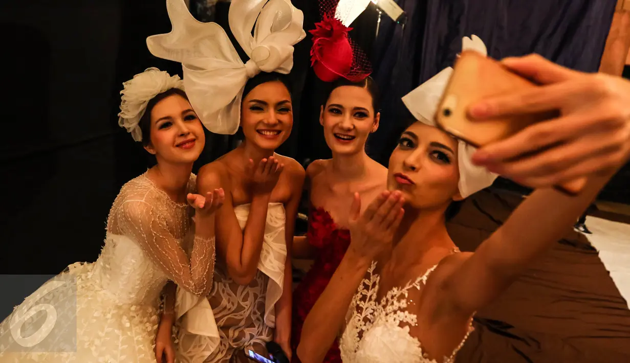 Sejumlah model saat selfie di ruang ganti sebelum pagelaran busana karya desainer Fetty Rusli di Hotel Mulia Senayan Jumat (26/02). Pagelaran dimulai seiring cahaya fajar keemasan di sebuah rumah besar menyerupai istana. (Liputan6.com/Fery Pradolo)