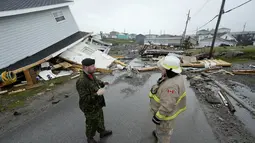 Warrant Officer Kelas 1 Bradley McInnes berbicara dengan petugas pemadam kebakaran di tengah-tengah rumah yang hancur di Port aux Basques, Newfoundland dan Labrador, Senin, 26 September 2022. Setelah melonjak ke utara dari Karibia sebagai badai besar, Fiona mendarat sebelum fajar Sabtu sebagai pos -siklon tropis, menerjang Nova Scotia, Pulau Prince Edward, Newfoundland dan Quebec dengan kekuatan angin topan, hujan, dan ombak. (Frank Gunn/The Canadian Press via AP)