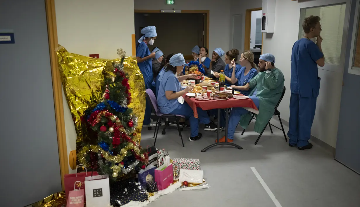 Dokter junior Tom Ballas melihat ke dalam kamar pasien saat dokter dan perawat makan bersama di malam Natal di unit perawatan intensif COVID-19 di rumah sakit la Timone di Marseille, Prancis selatan, Jumat (24/12/2021). (AP Photo/Daniel Cole)