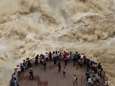Wisatawan menikmati pemandangan mengerikan derasnya arus sungai Jinsha dari tempat wisata Tiger Leaping Gorge di Diqing, Provinsi Yunnan, China (15/7). (REUTERS / Stringer)