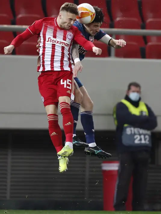 Bek Olympiakos, Oleg Reabciuk berebut bola dengan bek Arsenal, Hector Bellerin pada leg pertama babak 16 besar Liga Europa di stadion Georgios Karaiskakis, Athena, Jumat (12/3/2021). Tiga gol di markas Olympiakos menjadi modal penting Arsenal untuk laga selanjutnya. (AP Photo/Thanassis Stavrakis)
