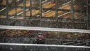 Seorang pria membentuk bola salju saaat hujan salju lebat turun saat di Universitas Simon Fraser, Burnaby, British Columbia, Kanada (21/12/2020). Hujan salju lebat juga melanda Taman Kensington Vancouver. (Darryl Dyck/The Canadian Press via AP)