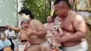 Dua orang bayi menangis saat digendong pegulat sumo dalam Lomba Bayi Menangis di kuil Irugi, Jepang, (21/9/14). (AFP PHOTO/ Yoshikazu TSUNO)