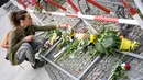Seorang wanita meletakkan bunga di depan Kedutaan Besar Perancis di Berlin, Jerman (15/7). Karangan bunga tersebut untuk menghormati para korban teror Truk Maut saat perayaan hari Bastille di Nice. (AFP PHOTO/John MacDougall)