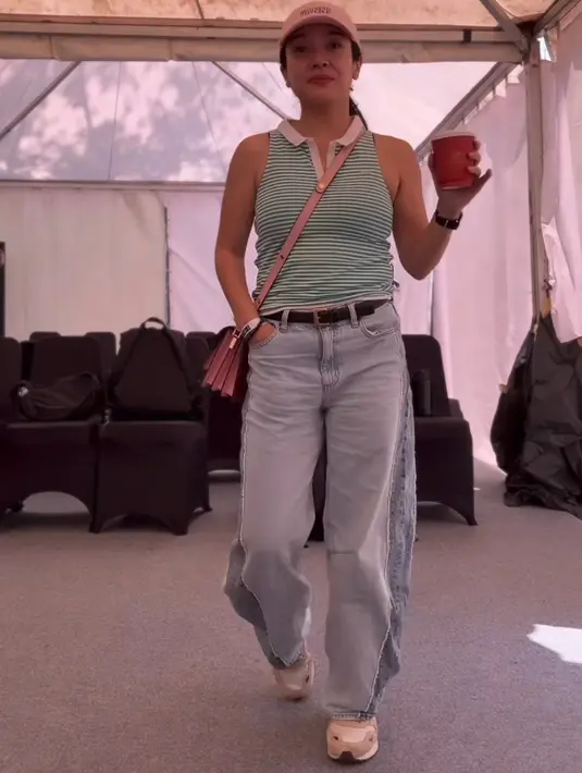 <p>Dea Ananda mengenakan atasan sleeves bergaris hijau kerah putih dipadukan belt hitam dan celana panjang denim. Ia mengenakan topi cap dan slingbag pink. [@dea_ananda]</p>