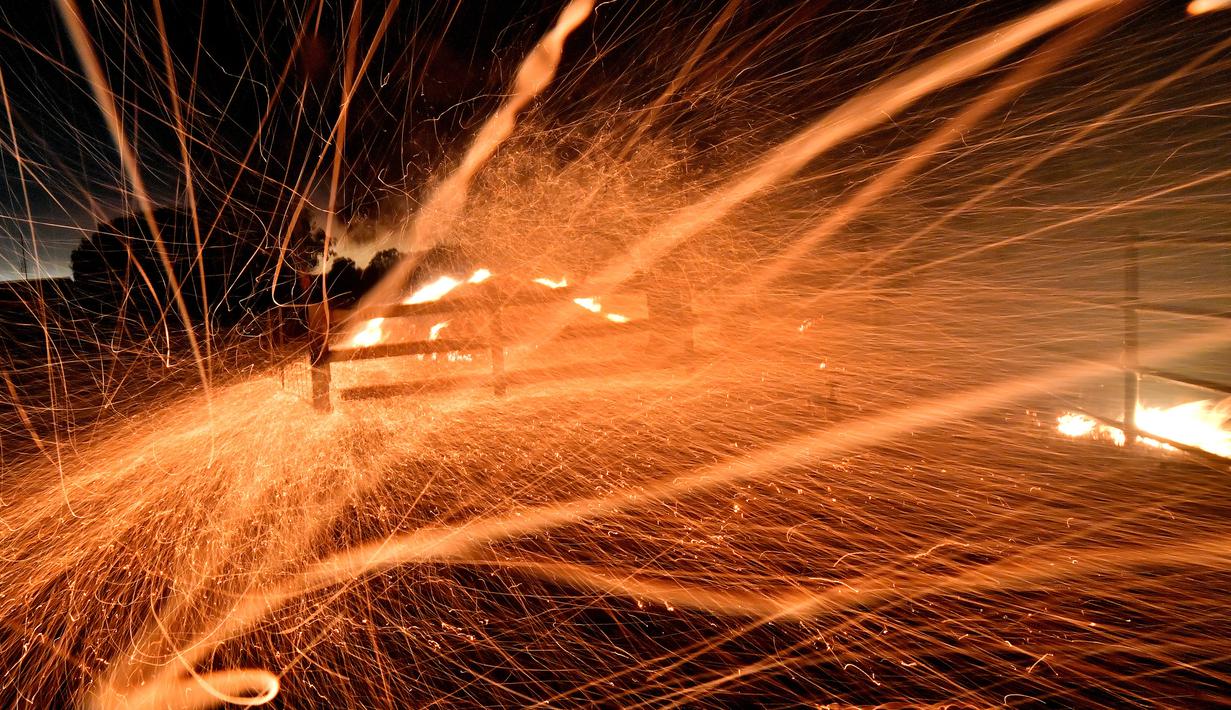 Bara api dari kebakaran hutan tertiup angin kencang di daerah sekitar kota Nowra, kota Nowra, negara bagian New South Wales, Australia, Selasa (31/12/2019). Akibat kebakaran ini, ribuan wisatawan dan penduduk lokal mengungsi ke wilayah pantai di Australia tenggara. (AFP/Saeed Khan)