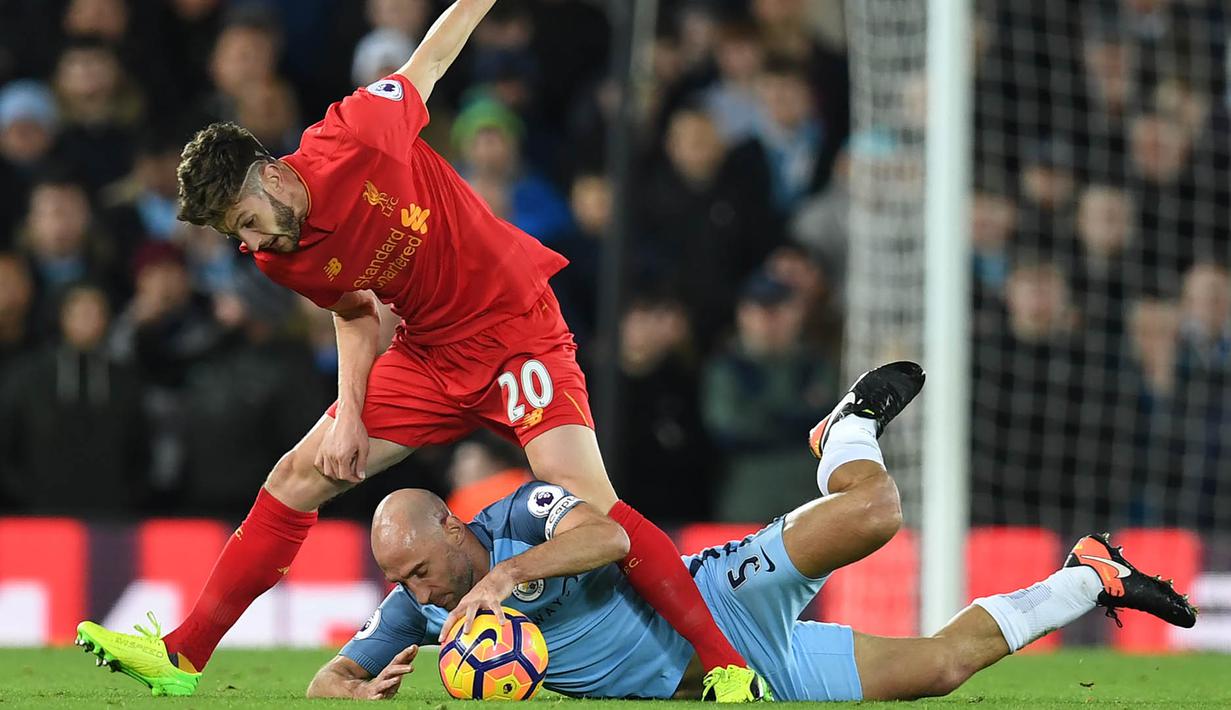 Bek Manchester City, Pablo Zabaleta, terjatuh berebut boola dengan gelandang Liverpool, Adam Lallana pada laga Liga Inggris di Stadion Anfield, Inggris, Sabtu (31/12/2016). (AFP/Paul Ellis)