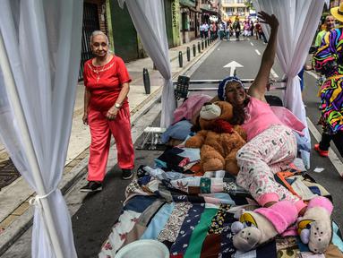 Seorang wanita Kolombia berbaring di tempat tidur saat ambil bagian dalam pawai merayakan Hari Kemalasan Sedunia di Itagui, dekat Medellin, Minggu (19/8). Upaya unik itu untuk medesak para perkerja yang tertekan agar bersantai. (AFP/JOAQUIN SARMIENTO)