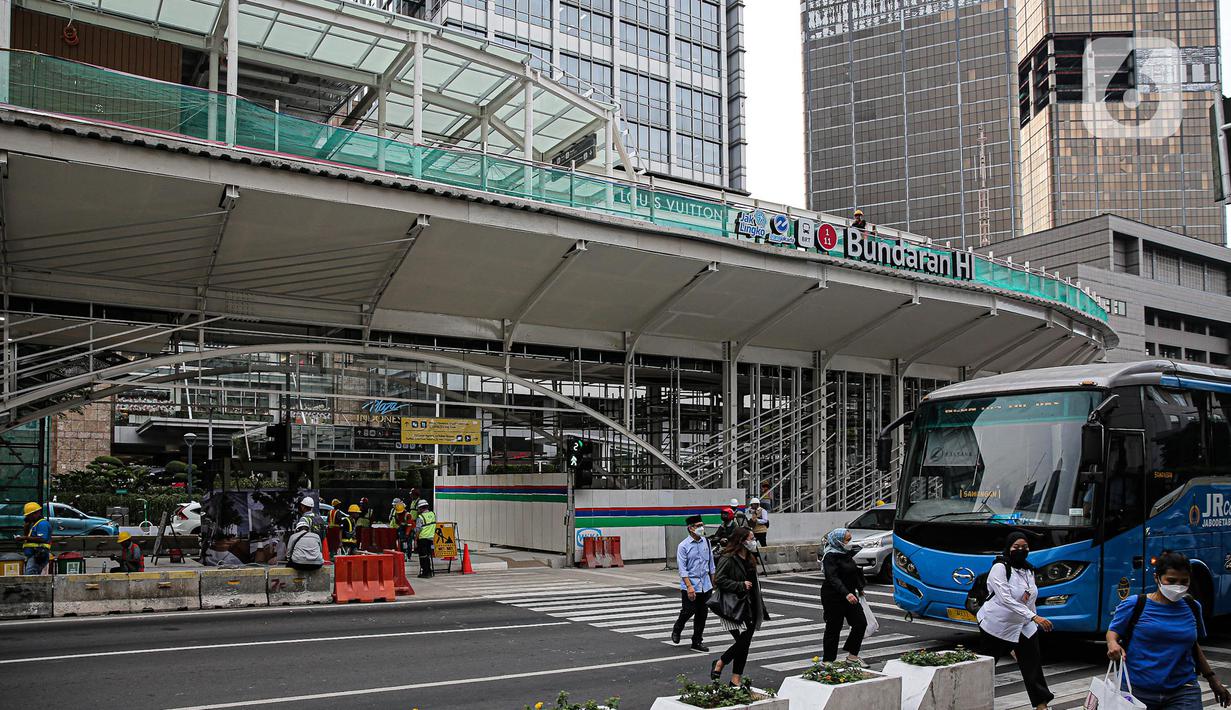 Pejalan kaki menyebrang di dekat proyek revitalisasi Halte TransJakarta Bundaran HI, Jakarta, Senin (3/10/2022). Gubernur DKI Jakarta Anies Baswedan memastikan revitalisasi halte Transjakarta Tosari di kawasan Bundaran HI terus berlanjut. Proyek revitalisasi itu terus berlanjut meskipun sempat diprotes sejarawan JJ Rizal karena dianggap menutupi Patung Selamat Datang di Bundaran HI. (Liputan6.com/Faizal Fanani)