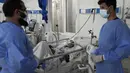 Dua dokter berbicara saat pasien COVID-19 terbaring di tempat tidur di ICU Rumah Sakit Penyakit Menular Afganistan-Jepang di Kabul, 7 Februari 2022. Afghanistan yang hancur secara ekonomi pekan lalu mengalami peningkatan 67 persen dalam jumlah kasus COVID yang dilaporkan. (AP Photo/Hussein Malla)