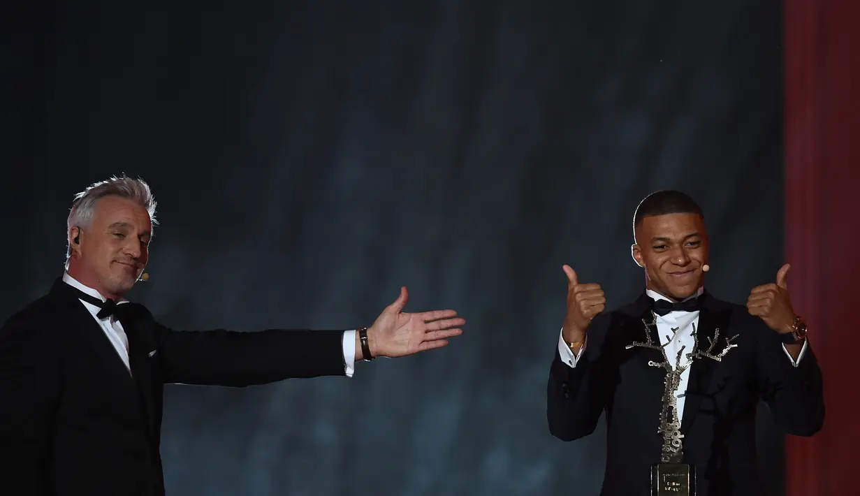 Striker PSG, Kylian Mbappe (kanan) bereaksi setelah menerima penghargaan Trophee Kopa pada seremoni Ballon d'Or 2018 di Paris, Senin (3/12). Mbappe menjadi pemain pertama dalam sejarah yang memenangi penghargaan Trophee Kopa. (FRANCK FIFE/AFP)