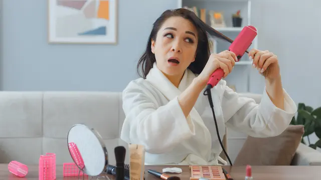 Seorang perempuan sedang mencatok rambutnya setelah mandi (Foto Dok: Freepik/stockking)