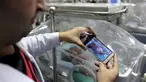 Perawat mengambil gambar bayi dengan kondisi kembar siam yang dirawat di dalam inkubator di RS Al Shifa, Kota Gaza, Rabu (23/11). Bayi ini memiliki dua kepala, dua hati, dua paru-paru, tetapi dada dan perutnya hanya satu. (REUTERS/Ibraheem Abu Mustafa)