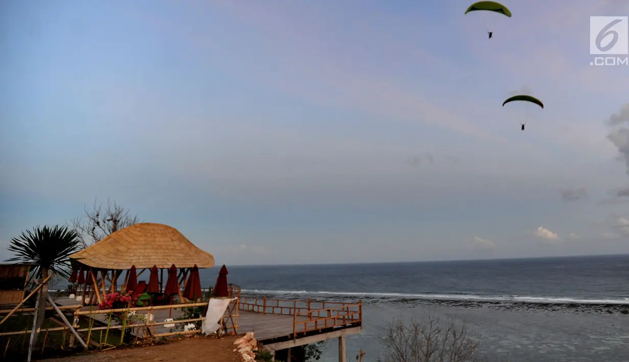 Wisatawan melakukan tandem paralayang di Bukit Riug, Nusa Dua, Bali (30/6). Kegiatan paralayang tandem dengan mengandalkan angin pantai sudah lebih dari satu tahun digemari para wisatawan mancanegara dan lokal. (Merdeka.com/Arie Basuki)