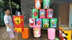 Seorang pengrajin lukis tong sampah membawa hasil karyanya yang siap dijual di kawasan serpong, Tangerang Selatan, Senin (20/3). Tong sampah bermotif karakter kartun tersebut di jual seharga 80-125 ribu. (Liputan6.com/Helmi Afandi)