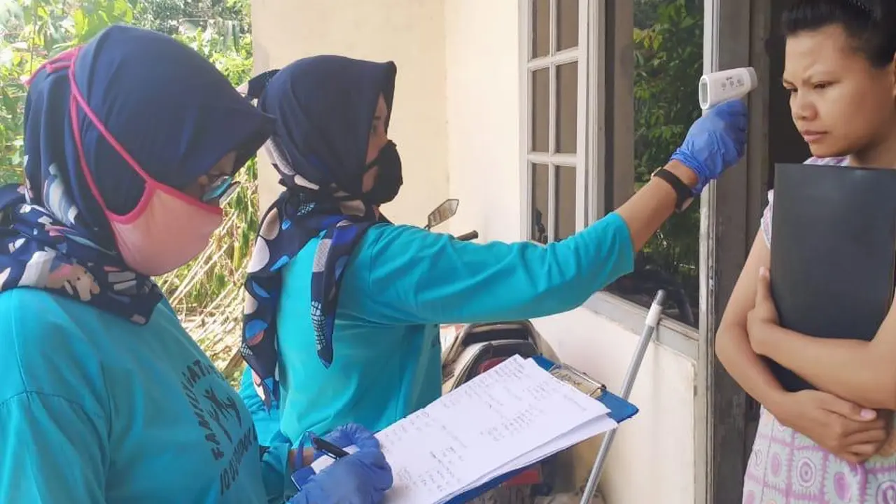 Petugas 10 rumah aman mengukur suhu warga.