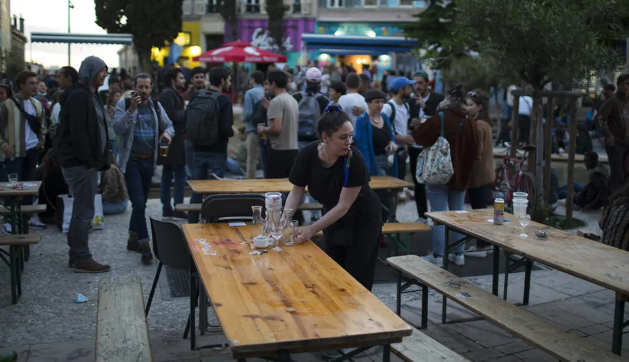 Seorang pelayan membersihkan meja setelah jam malam di Marseille, Prancis, Rabu (19/5/2021). Prancis kembali membuka kafe dan restoran pada 19 Mei 2021 setelah ditutup lebih dari enam bulan karena pandemi virus corona COVID-19. (AP Photo/Daniel Cole)