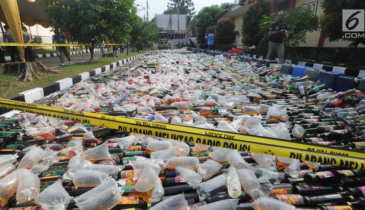 Alat berat menggilas ribuan botol minuman keras  (miras) hasil sitaan polisi di halaman Polres Bogor, Cibinong, Kamis (17/5). Miras yang dimusnahkan lebih dari 32 ribu botol, baik lokal maupun impor dengan beragam merek. (Merdeka.com/Arie Basuki)