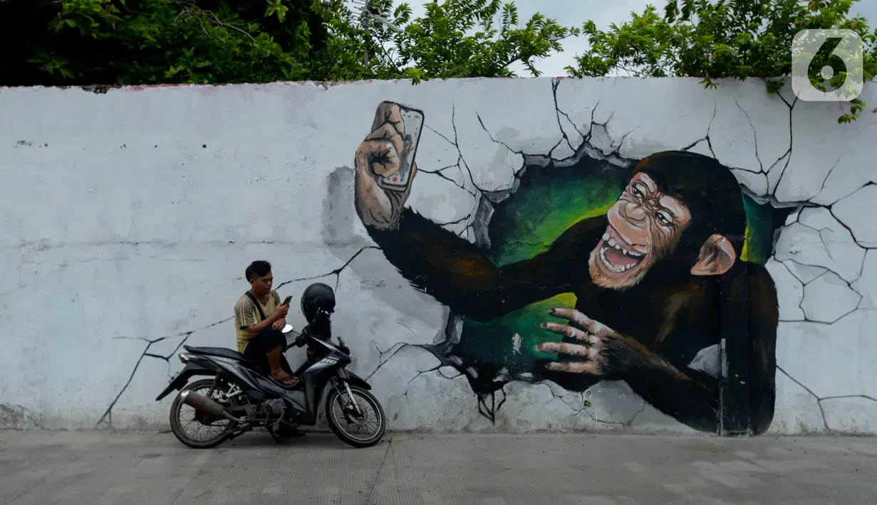 Pengendara berhenti dekat kreasi mural di sepanjang dinding bantaran Kali Opak, Jakarta Utara, Kamis (6/2/2020). Tembok bangunan saat ini tak hanya menjadi pembatas semata tapi dimanfaatkan untuk menyampaikan pesan-pesan dan harapan dalam bentuk goresan atau tulisan. (merdeka.com/Imam Buhori)