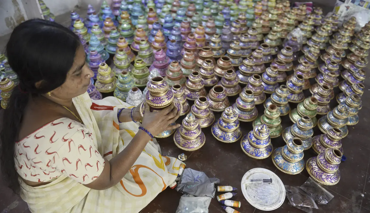 Perajin menunjukkan pot minyak tembikar atau diyas yang disimpan untuk dikeringkan menjelang Diwali, festival lampu Hindu, di luar bengkel di Hyderabad (4/11/2020). Diwali dirayakan selama lima hari berturut-turut. (AFP Photo/Noah Seelam)