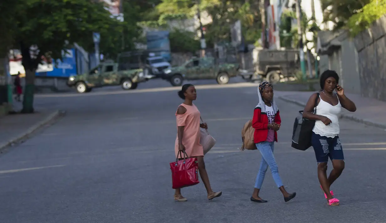 Orang-orang berjalan melewati kendaraan militer yang menghalangi pintu masuk ke Petion Ville, lingkungan tempat mendiang Presiden Haiti Jovenel Moise tinggal di Port-au-Prince, Haiti, Rabu (7/7/2021).  (AP Photo/Joseph Odelyn)