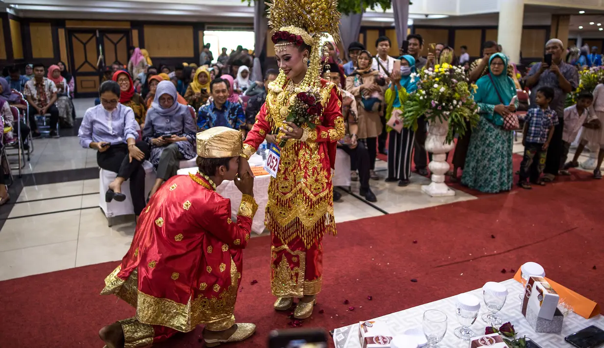 Pasangan pengantin saat mengikuti nikah massal di Surabaya, Jawa Timur, Rabu (18/12/2019). Sebanyak 60 pasangan pengantin mengikuti nikah massal yang digelar Dinas Sosial Kota Surabaya. (JUNI KRISWANTO/AFP)