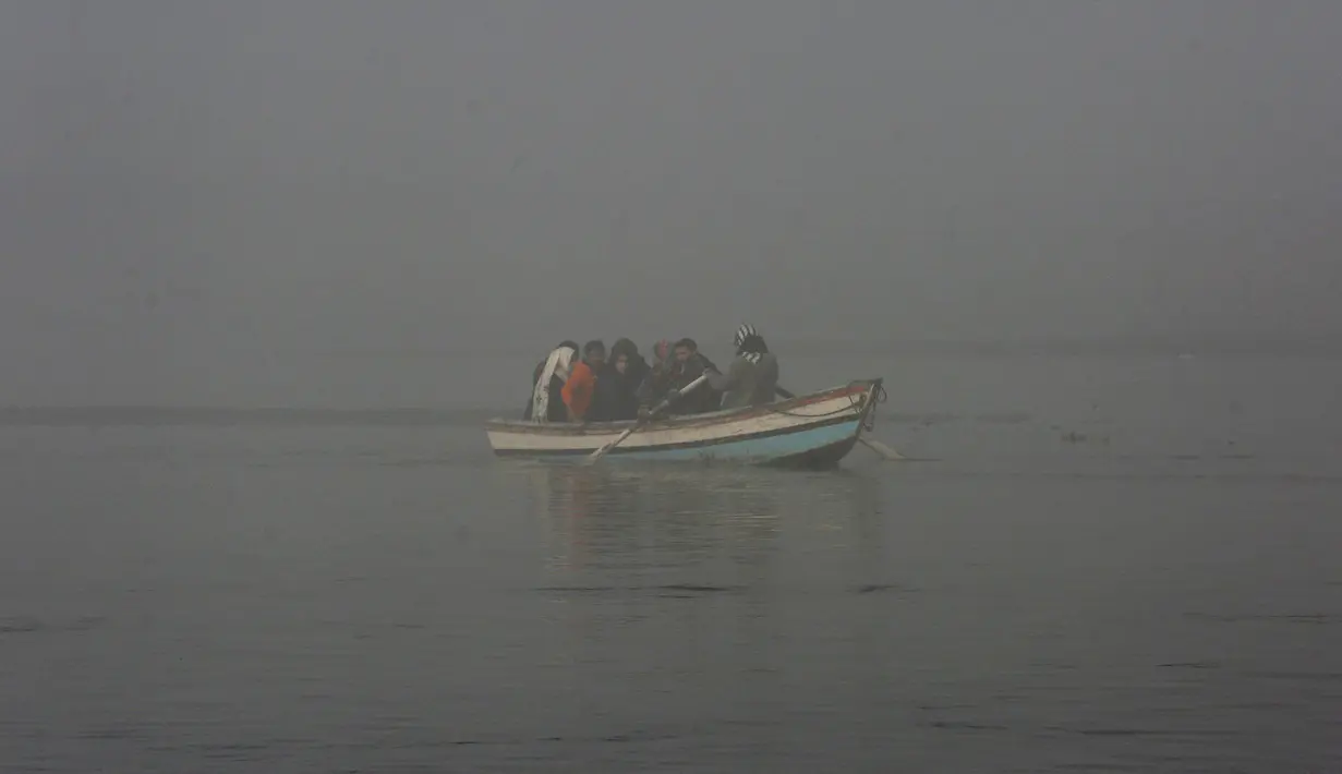 Orang-orang naik perahu di Sungai Ravi saat kabut tebal menyelimuti Lahore, Pakistan, Selasa (30/11/2021). Lahore secara konsisten menempati peringkat sebagai salah satu kota terburuk di dunia untuk polusi udara. (AP Photo/K.M. Chaudary)
