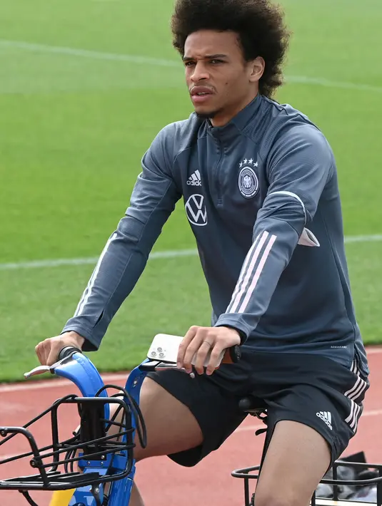 Gelandang Jerman, Leroy Sane tiba dengan sepeda sebelum sesi latihan menjelang UEFA EURO 2020 di World of Sports Campus di Herzogenaurac (11/6/2021). Pada pertemuan pertama, Jerman akan bertemu Prancis pada grup F di Allianz Arena, Rabu (16/6). (AFP/Christof Stache)