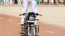 Anggota polisi India berdiri di atas motor sambil memegang payung saat beratraksi mengikuti parade di Pusat Pelatihan Polisi Rajasthan di Jodhpur, India, Jumat (24/4/2015).(AFP FOTO)