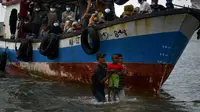 Nelayan Aceh membantu evakuasi seorang anak pengungsi etnis Rohingya menuju pesisir pantai desa Lancok, di Kabupaten Aceh Utara, Kamis (25/6/2020). Hampir 100 orang etnis Rohingya, termasuk 30 orang anak-anak ditemukan terdampar di tengah laut dengan kondisi kapal rusak. (CHAIDEER MAHYUDDIN/AFP)