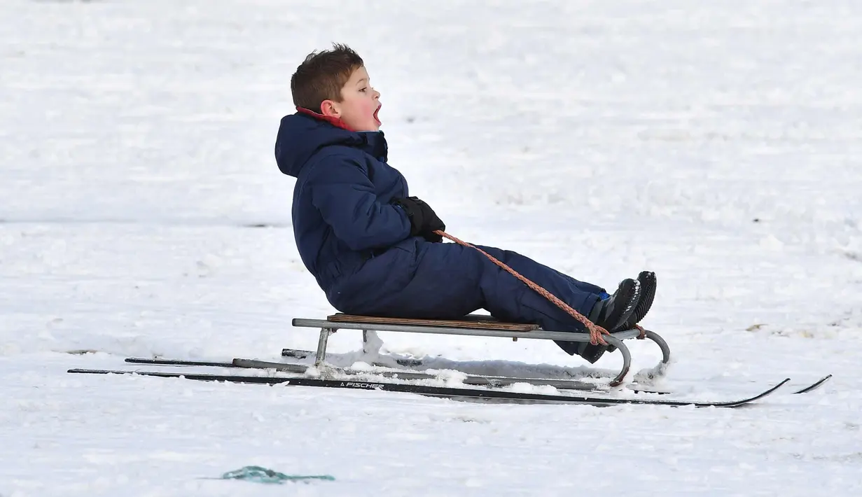 Seorang anak bermain kereta luncur selama hujan salju di taman Dunorlan di Tunbridge Wells, Inggris (27/2). Cuaca dingin di Siberia yang dijuluki "The Beast from the East" membuat suhu di sebagian Eropa menurun. (AFP Photo/Ben Stansall)