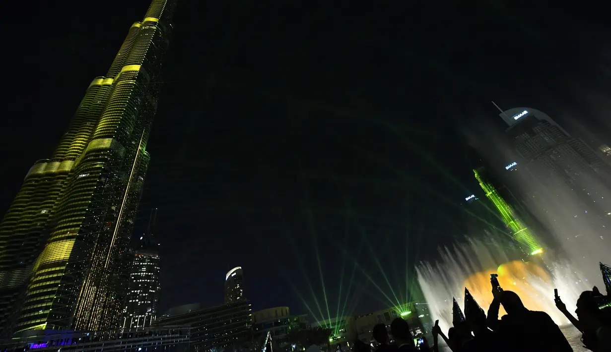 Pengunjung mengambil gambar pertunjukan sinar laser dari menara tertinggi dunia, Burj Khalifa, di Dubai, 31 Desember 2017. Pertunjukkan ini memecahkan rekor dunia Guinness dengan pertunjukan Light Up 2018 termegah di Malam Tahun Baru (Giuseppe CACACE/AFP)