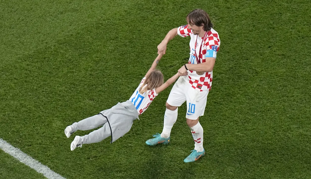 <p>Kapten Kroasia Luka Modric mengayunkan putrinya Sofia untuk merayakan kemenangan timnya melawan Maroko pada pertandingan playoff perebutan peringkat ketiga Piala Dunia 2022 di Khalifa International Stadium di Doha, Qatar, Sabtu (17/12/2022). Kroasia menang 2-1 atas Maroko. (AP Photo/Pavel Golovkin)</p>