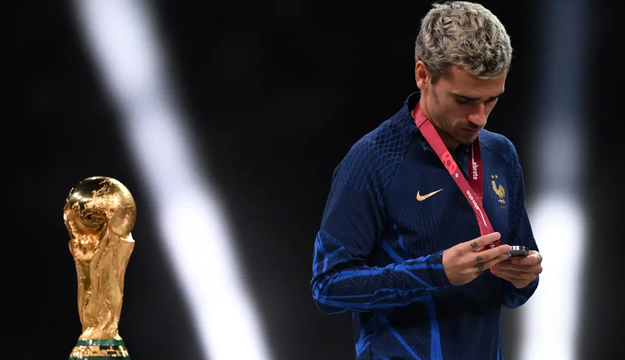 Sepanjang kariernya di timnas Prancis, Antoine Griezmann mencatat 137 kali bermain dan mencetak 44 gol. Tampak dalam foto, Antoine Griezmann melihat medali peraknya saat berjalan saat upacara penyerahan trofi Piala Dunia Qatar 2022 di Stadion Lusail, Doha pada tanggal 18 Desember 2022. (Kirill KUDRYAVTSEV/AFP)