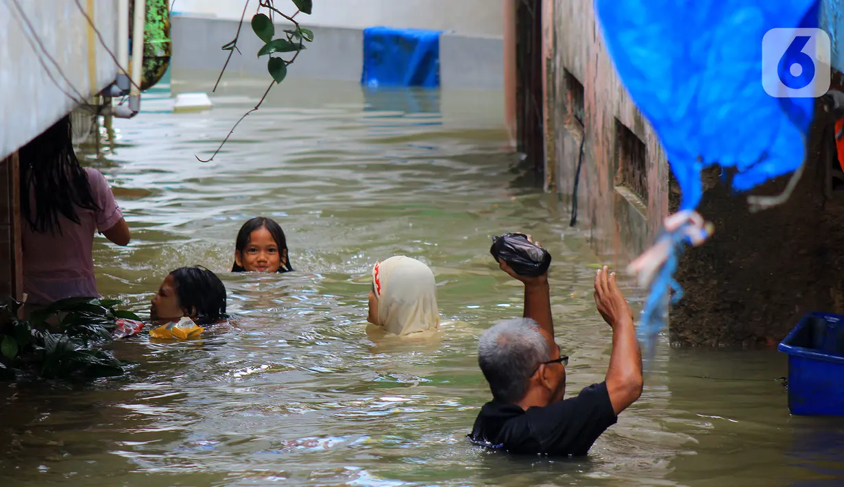 Aktivitas warga di tengah banjir yang merendam kawasan Kampung Melayu Kecil, Bukit Duri, Jakarta, Selasa (25/2/2020). Banjir tersebut akibat luapan sungai Ciliwung. (merdeka.com/magang/ Muhammad Fayyadh)