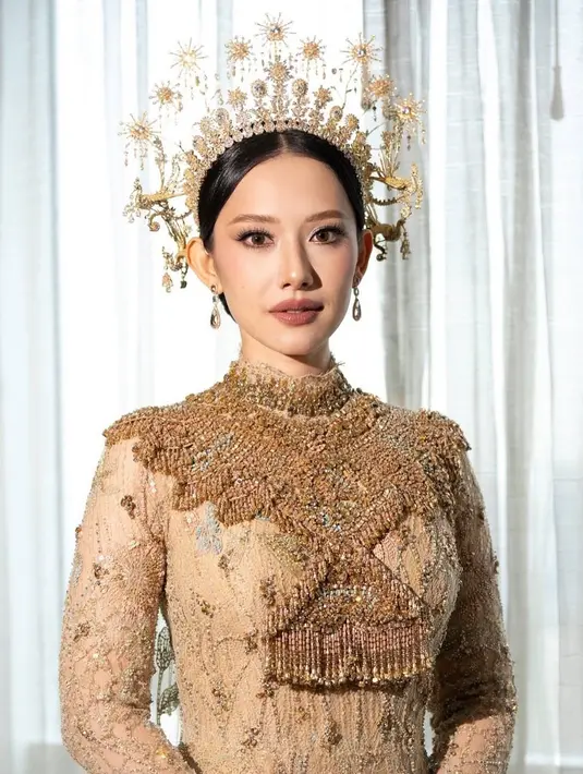 Ia mengenakan busana bernuansa keemasan rancangan Biyan dengan Tiara bagai serang Dewi. [Foto: Instagram/ The Bridestory]